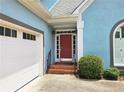 Close-up of a home's brick-lined entrance leading to a red front door with a white garage door to its side at 3740 Ashford Ne Pt, Brookhaven, GA 30319