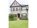 Charming two-story home with a brick facade, complemented by a well-manicured lawn and colorful flower beds at 4020 Alligator Pt, Cumming, GA 30028