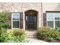 Inviting front entrance with brick archway, dark wood door, and manicured landscaping at 4020 Alligator Pt, Cumming, GA 30028