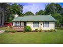 Charming one-story home featuring a green metal roof, inviting front deck, and lush lawn at 173 Elder Dr, Social Circle, GA 30025