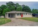 Single-story home boasting a long driveway, carport, a bright red front door and brick facade at 2290 Pope Rd, Douglasville, GA 30135