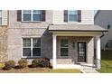 Inviting townhome entrance featuring a covered porch, manicured shrubs, and brick facade at 2692 Pearl Ridge Trce, Buford, GA 30519