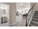 Modern entryway with staircase, open to kitchen featuring island, and half bath with pedestal sink at 213 Yellowwood Way, Woodstock, GA 30188