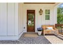 Inviting front porch featuring brick flooring, wooden bench, and a charming wooden front door at 3617 Carson Se Ln, Smyrna, GA 30080