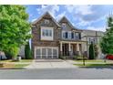 Charming two-story home featuring a covered porch, attached garage and manicured lawn at 828 Olmsted Ln, Duluth, GA 30097