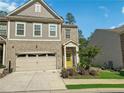 Charming two-story home with a brick facade, two-car garage, landscaped yard and a welcoming, bright yellow front door at 150 Holden Way, Woodstock, GA 30189
