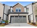 Inviting townhome with a gray two-car garage, brick, and siding, offering a modern curb appeal at 2440 Rocky City Ln, Snellville, GA 30078