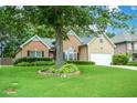 Home featuring a large tree in the front yard, brick and siding exterior, and manicured landscaping at 9013 Aldbury Dr, Locust Grove, GA 30248
