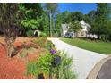 The driveway leads to a charming two-story home surrounded by trees, landscaping, and flowering bushes at 811 Millvale Pl, Lawrenceville, GA 30044