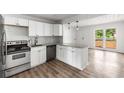 A modern kitchen featuring stainless steel appliances, new white cabinets, and a granite countertop island at 6932 Eunice Dr, Riverdale, GA 30274