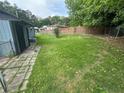 Spacious backyard featuring green grass, a chain-link fence, and a small storage unit at 3730 Clovis Nw Ct, Atlanta, GA 30331