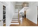 Elegant foyer with hardwood floors, staircase, and a stylish mirror reflecting the kitchen at 12230 Asbury Park Dr, Roswell, GA 30075
