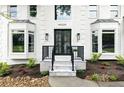 Charming home entrance featuring a black iron door, stylish stone steps, and attractive landscaping at 12230 Asbury Park Dr, Roswell, GA 30075
