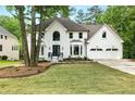 Gorgeous home with green lawn, mature trees, a two-car garage, and beautiful landscaping at 12230 Asbury Park Dr, Roswell, GA 30075