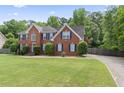Lovely brick home boasts a spacious front yard, blue shutters and established greenery, offering great curb appeal at 129 Crown Walk, Mcdonough, GA 30253