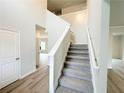 Inviting foyer featuring a carpeted staircase, neutral walls, and stylish wood-look flooring at 5342 Legacy Trl, Douglasville, GA 30135