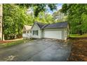 A beautiful single story home with an attached garage and a long driveway is surrounded by lush trees at 1154 Pinebrook Rd, Auburn, GA 30011