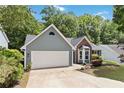 Gray home featuring a two-car garage, nicely kept lawn, and mature trees in the background at 231 Clarion Rd, Lawrenceville, GA 30043
