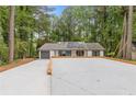 Ranch home exterior showing the driveway, white siding, new roof with solar panels, and attached garage surrounded by mature trees at 3216 Montheath Ct, Duluth, GA 30096