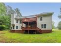 Two-story home featuring a spacious wooden deck, brick foundation, and lush green lawn at 7406 Cherry Blossom Way, Winston, GA 30187