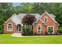 Charming red brick home featuring an immaculate lawn, arched windows, and professional landscaping at 7406 Cherry Blossom Way, Winston, GA 30187