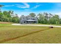 Beautiful gray farmhouse with a long driveway, expansive lawn, and mature trees at 157 Palisade Ne Dr, Rydal, GA 30171