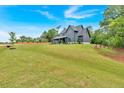 Scenic view of a modern gray farmhouse on a lush green lot with surrounding trees at 157 Palisade Ne Dr, Rydal, GA 30171