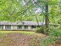 Rear view of a single-story home with painted brick and dark shutters surrounded by lush trees and vegetation at 161 E 78 Hwy, Temple, GA 30179