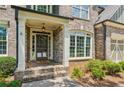 Close-up of a brick home's front porch with white columns, a dark door, and manicured landscaping at 1320 Magnolia Park Cir, Cumming, GA 30040