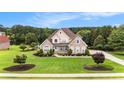 Aerial view of brick home with lush lawn, mature trees, and established landscaping on a sunny day at 127 Courts Of Hampton, Hampton, GA 30228