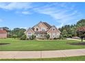 Beautiful brick home with a well-manicured lawn and mature landscaping in a suburban neighborhood at 127 Courts Of Hampton, Hampton, GA 30228
