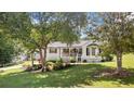 A beautiful exterior of a cozy, white house with a front porch nestled amongst mature trees in a lush, green yard at 2675 Springside Ct, Douglasville, GA 30135