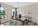 Bright dining room featuring paneled accent wall, modern lighting, and views of the outdoors through large windows at 4297 Azalea Ridge Way, Hoschton, GA 30548