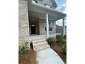 Inviting covered front porch with brick steps and decorative landscaping at 4297 Azalea Ridge Way, Hoschton, GA 30548