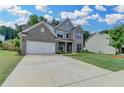 Charming two-story home with gray brick, wide driveway, and lush green lawn at 5215 Wheeler Run Dr, Auburn, GA 30011