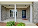 Cozy front porch with brick facade, white columns, and a welcoming black front door at 5215 Wheeler Run Dr, Auburn, GA 30011