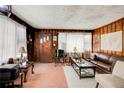 Living room with wood-paneled walls, mixed flooring, and a worn leather couch at 2293 Ewing Sw St, Atlanta, GA 30331