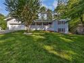 Charming home exterior with white porch, red shutters, a manicured lawn and large shade tree at 5142 Golfbrook Ct, Stone Mountain, GA 30088