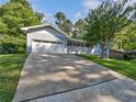 Inviting home exterior with a long driveway, garage, quaint porch and lush green lawn at 5142 Golfbrook Ct, Stone Mountain, GA 30088