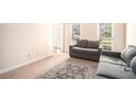 Cozy living room with a comfortable grey couch, area rug, and natural light from the large window at 5633 Southland Dr, Stone Mountain, GA 30087