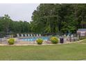 Community pool with many lounge chairs surrounded by trees, offering a relaxing outdoor space for residents at 2101 Emerald Dr, Loganville, GA 30052