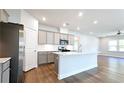 Modern kitchen featuring gray cabinets, stainless steel appliances, a large island, and hardwood floors at 621 Pineberry Ct, Grayson, GA 30017