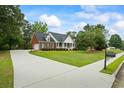 Inviting brick home boasts a long driveway, lush lawn, and charming front porch and manicured shrubs at 1253 Oakwood Pl, Loganville, GA 30052