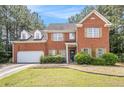 Charming two-story brick home with well-manicured lawn, mature trees, and an attached two-car garage at 2451 Broad River Pl, Ellenwood, GA 30294