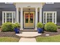 Inviting front entrance featuring a bright yellow double door, flanked by potted plants and manicured hedges at 6815 Berkley Rd, Cumming, GA 30040