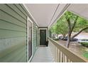 Covered front porch of a green home with a dark front door, white railings, and lush trees at 2808 Vinings Central Se Dr, Atlanta, GA 30339