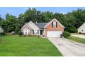 Inviting brick home featuring a well-maintained lawn and a convenient two-car garage and tree lined backyard at 1290 Silverstone Trl, Jonesboro, GA 30238