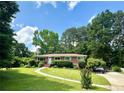 Inviting brick ranch home featuring a manicured lawn, mature trees, and a charming walkway at 388 Talcott Nw Cir, Marietta, GA 30064