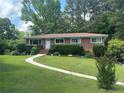 Inviting one-story brick home featuring a lush green lawn, manicured shrubs, and a curved walkway to the front door at 388 Talcott Nw Cir, Marietta, GA 30064