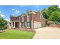Side view of a stately brick home with a three-car garage and well-manicured lawn and garden at 4541 Meadow Club Dr, Suwanee, GA 30024